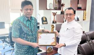 kepala Dinas Pemberdayaan Masyarakat dan Desa H Rusman, SE, MM menyerahkan sertifikat penghargaan kepada Bupati OKU Timur Ir H Lanosin ST.
